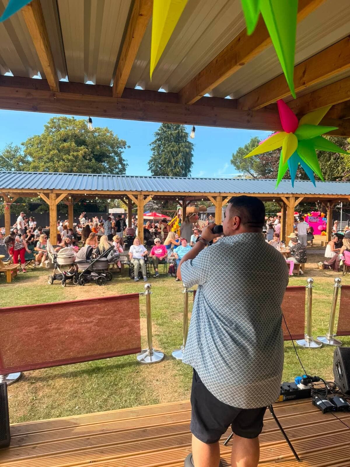 The view from the stage at the WN7 FEST Garden Party — a singer facing a crowd of families in camping chairs at The Comfortable Gill, Leigh