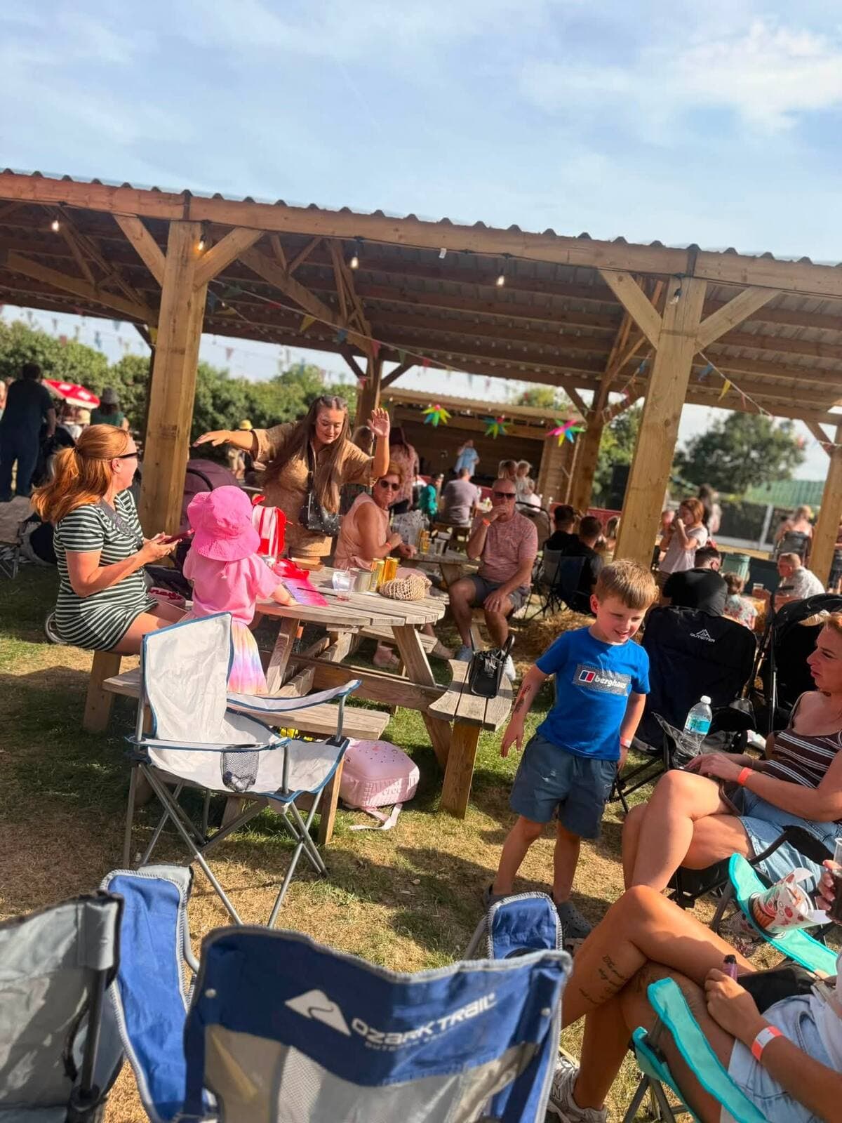 Families packed onto picnic benches under the timber shelter at the WN7 FEST Garden Party