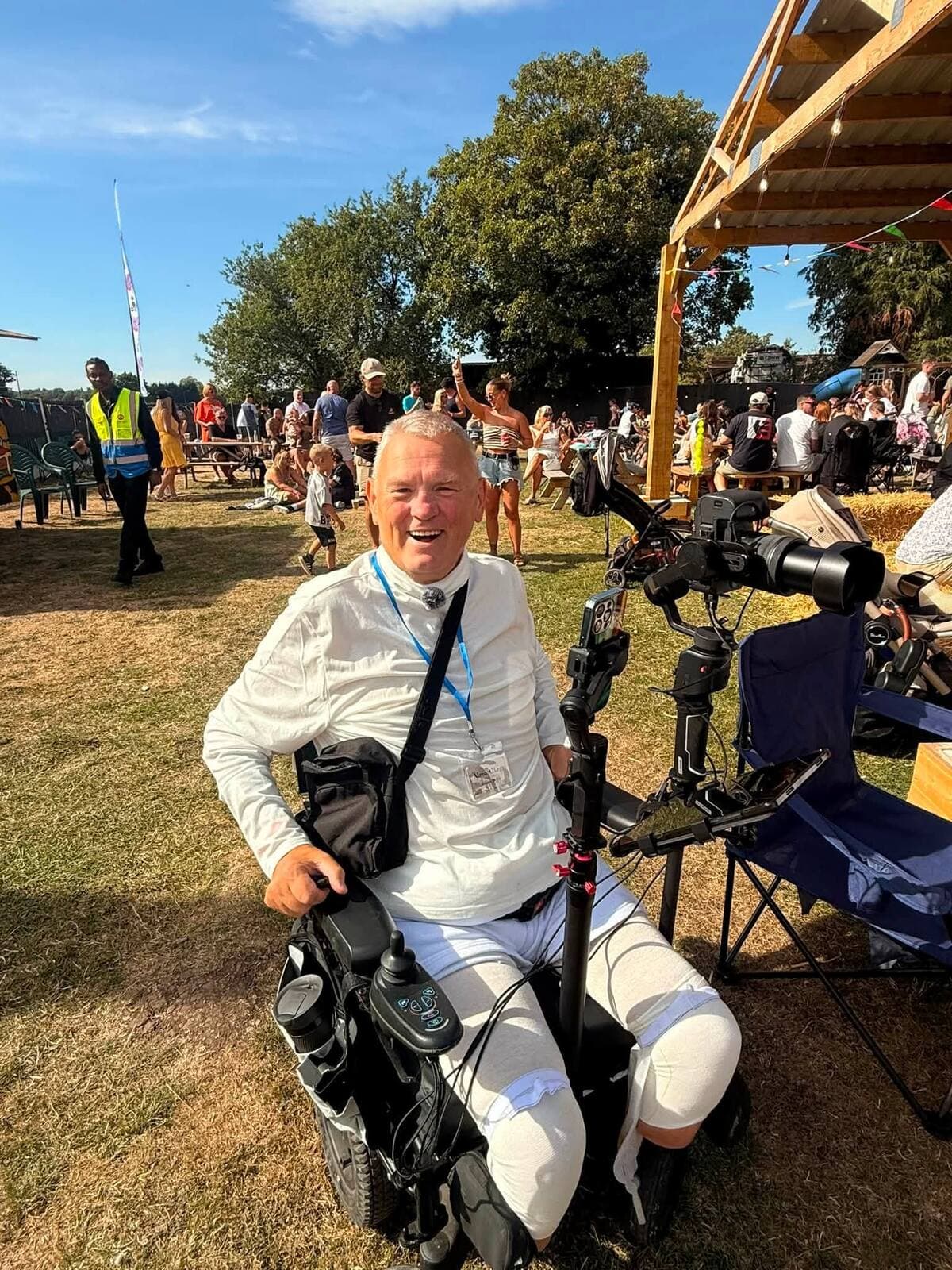 A wheelchair user grinning in the afternoon sunshine at The Comfortable Gill Garden Party