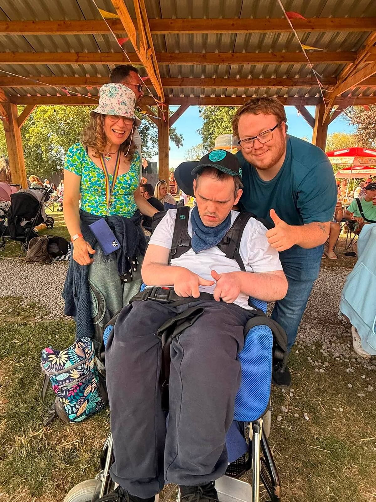 Three friends, one a wheelchair user, giving a thumbs up at the WN7 FEST Garden Party
