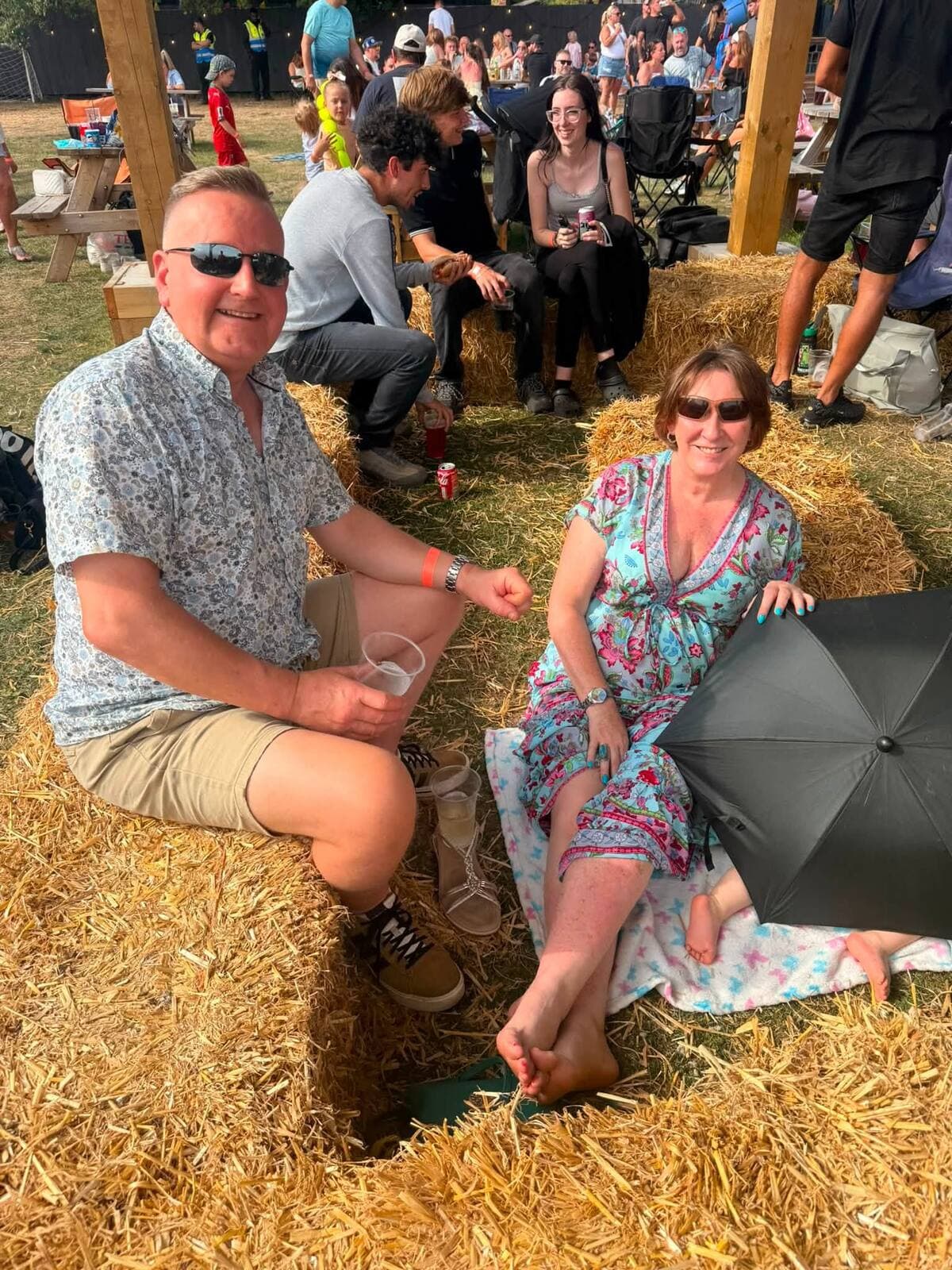 A couple relaxing on hay bales with a drink at the WN7 FEST Garden Party