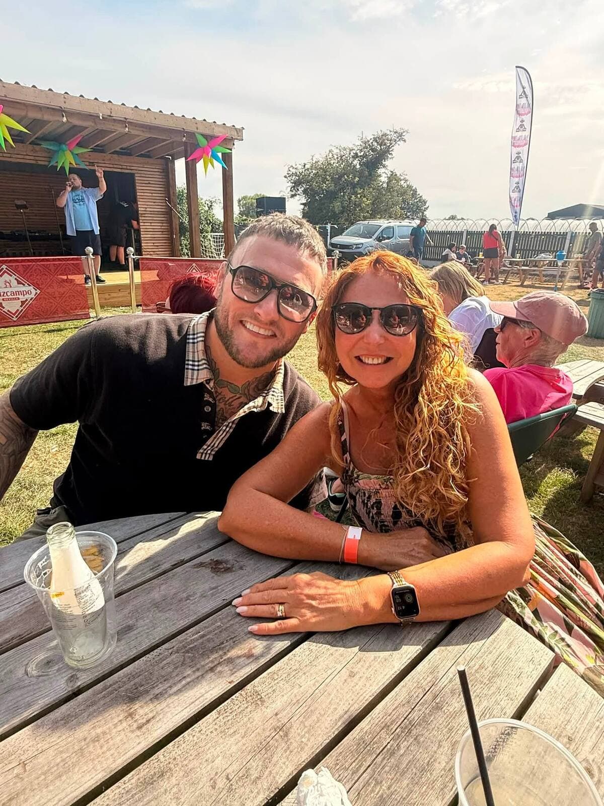 A couple at a picnic table with the main stage behind at the WN7 FEST Garden Party