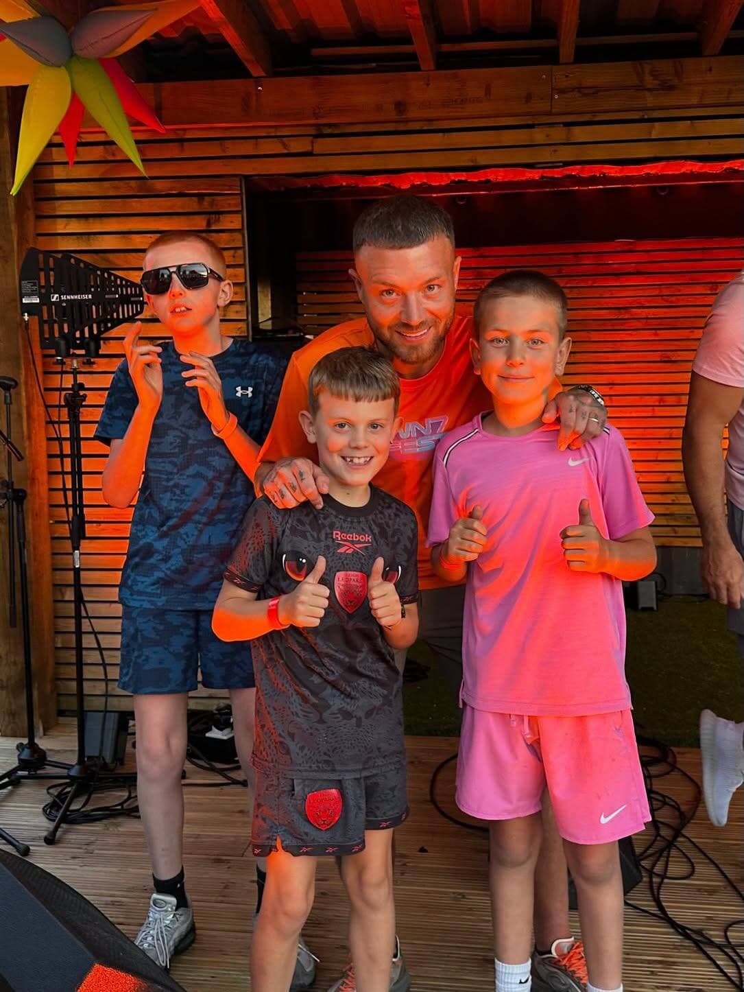 Three boys on stage with one of the acts at the WN7 FEST Garden Party